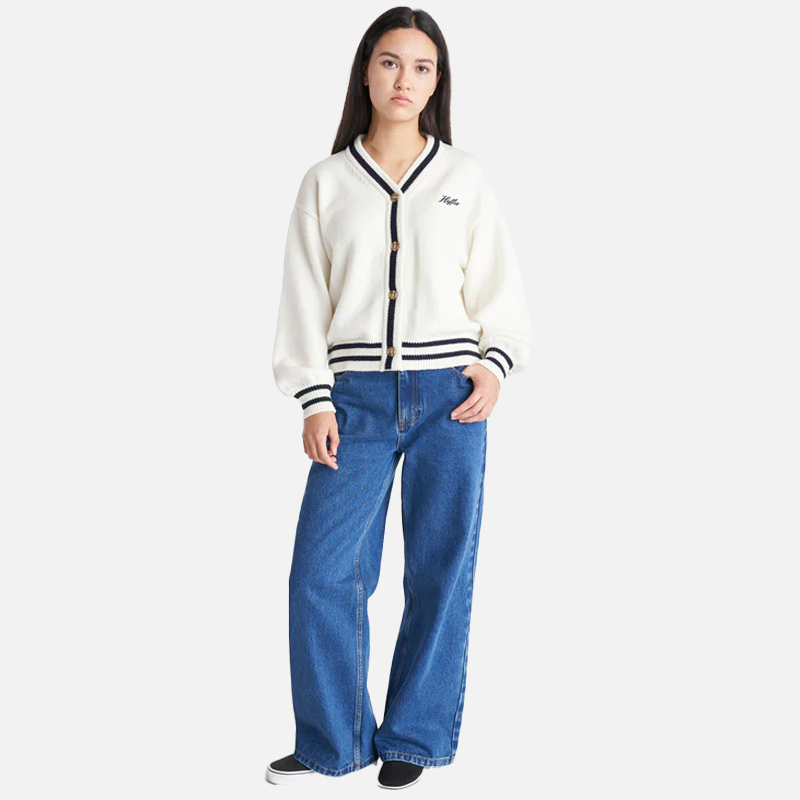 Person wearing a white cardigan with black trim and blue jeans on a white background