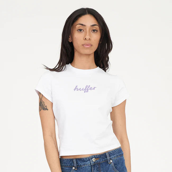 Woman wearing a white crop top with 'huffer' logo and a denim skirt on a white background