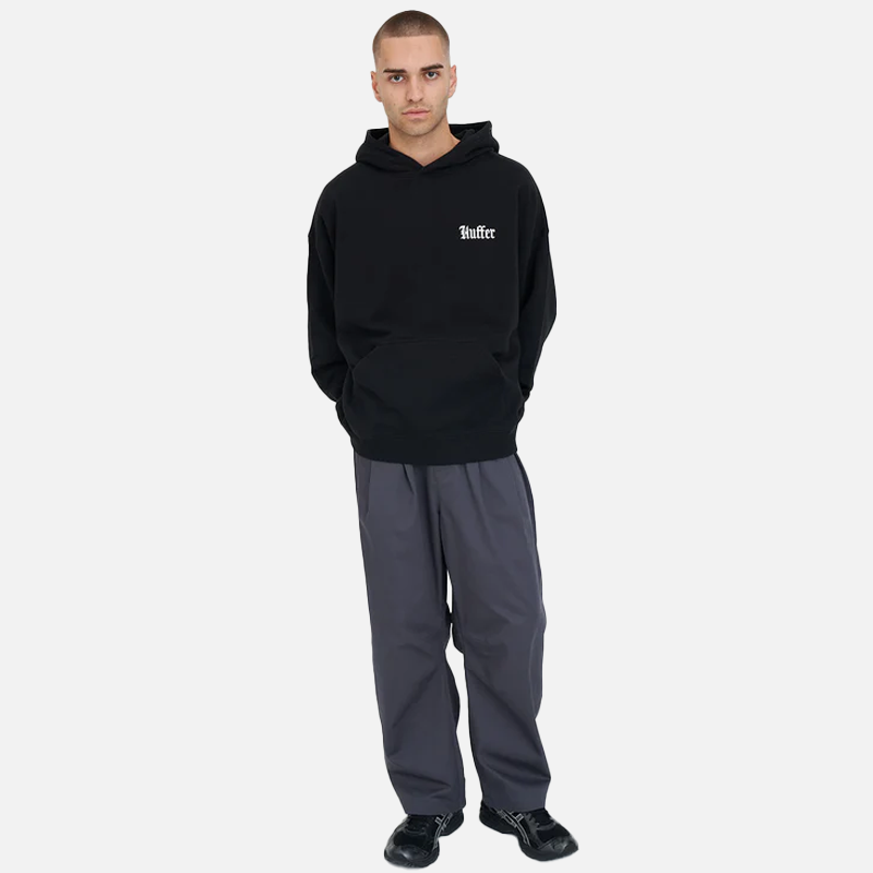 Man wearing a black hoodie with a logo and gray pants on a white background