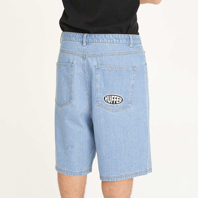 Light blue denim shorts with a brand logo worn by a person on a white background