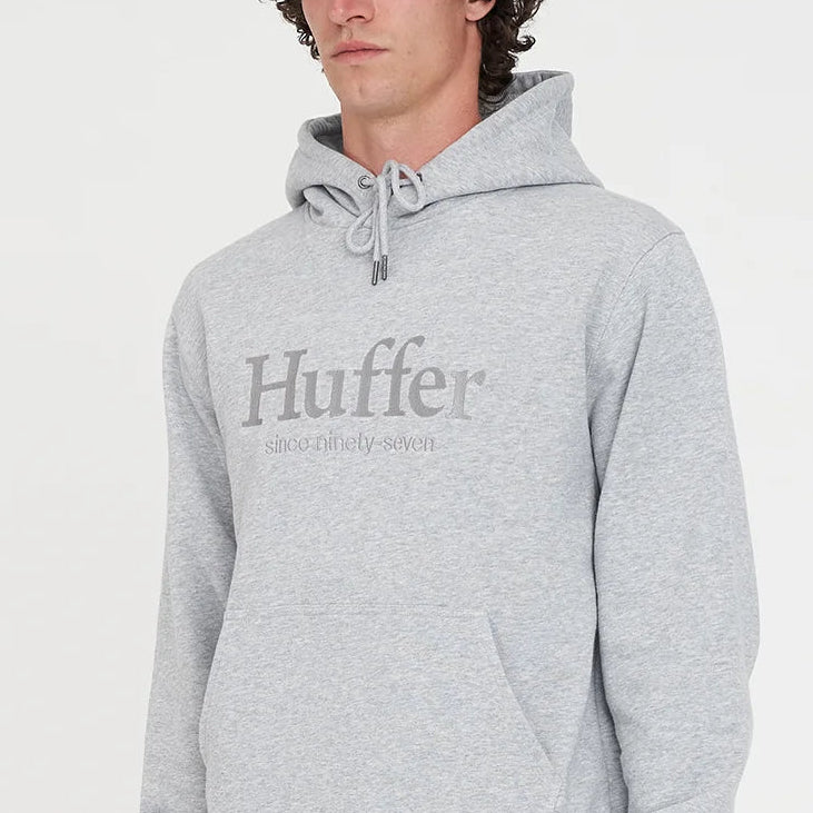 Person wearing a gray hoodie with 'Huffer' logo on a white background