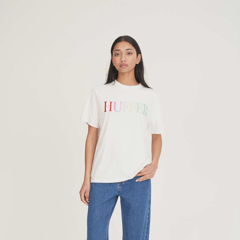 Person wearing a white t-shirt with colorful text and blue jeans on a white background