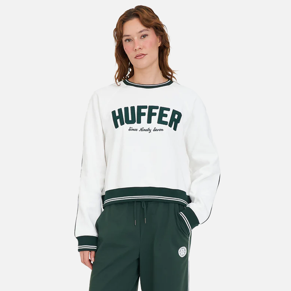 Person wearing a white sweatshirt with 'Huffer' logo and green pants on a white background