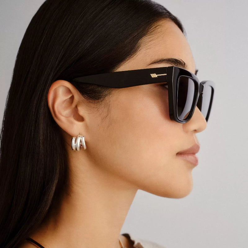 Woman wearing black sunglasses with a neutral background