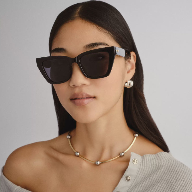 Woman wearing black sunglasses with a neutral background
