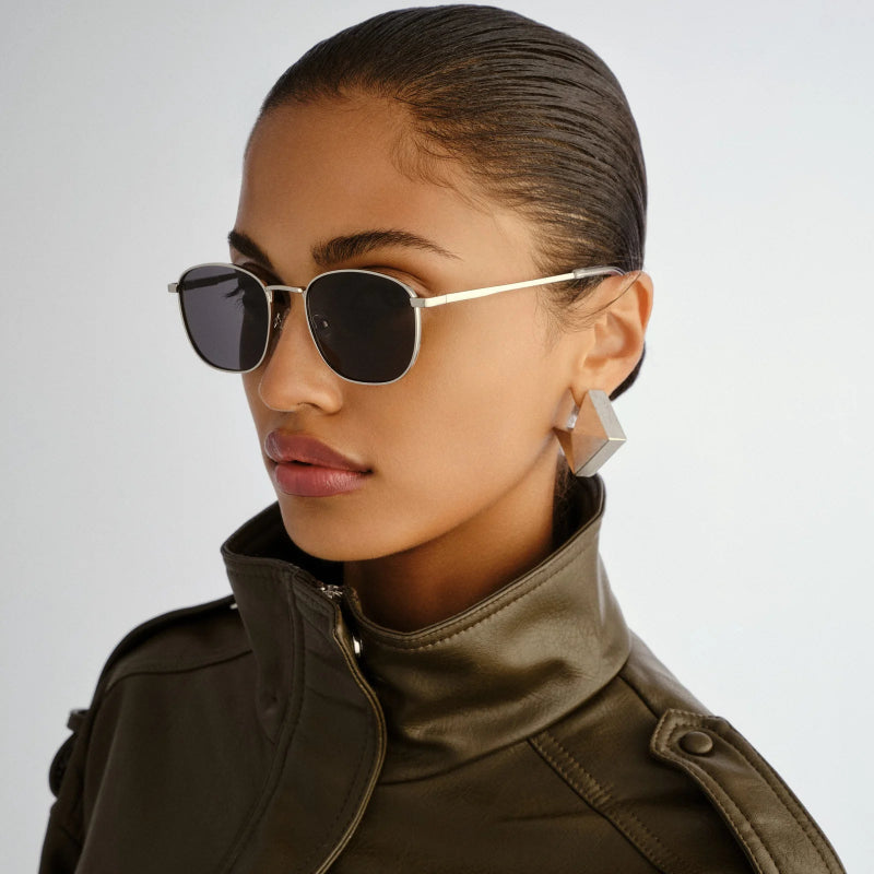 Woman wearing sunglasses and a green jacket on a light gray background