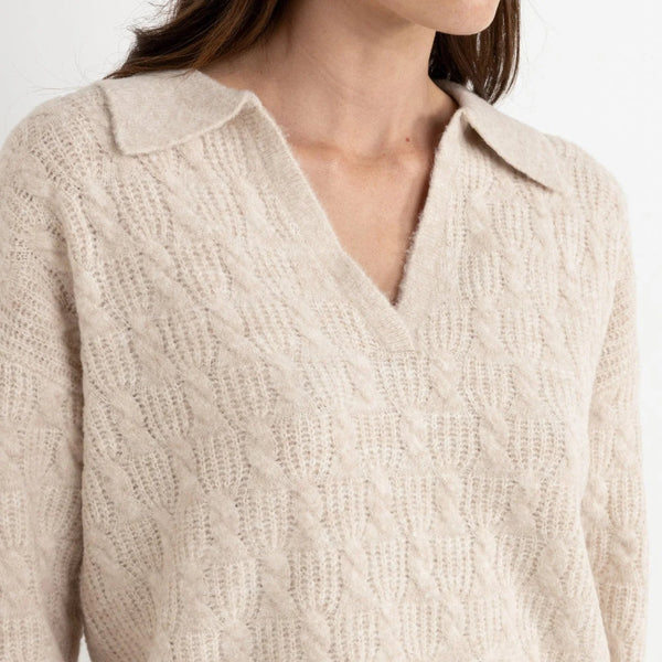 Beige cable knit sweater worn by a person on a light background
