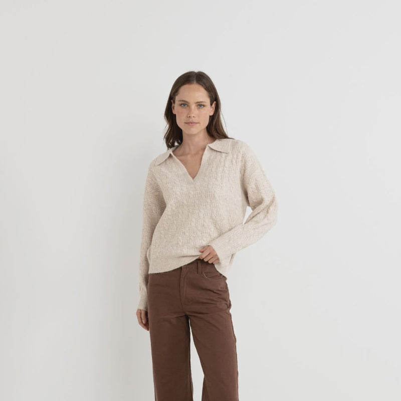 Woman wearing a beige shirt and brown pants on a white background