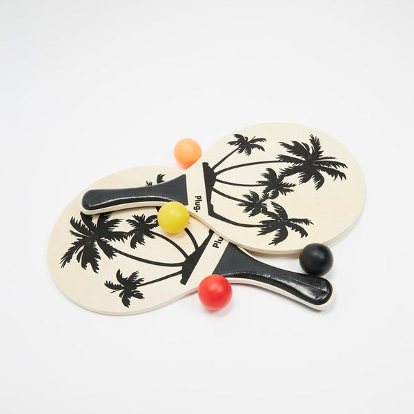 Two wooden paddle balls with palm tree design on a white background
