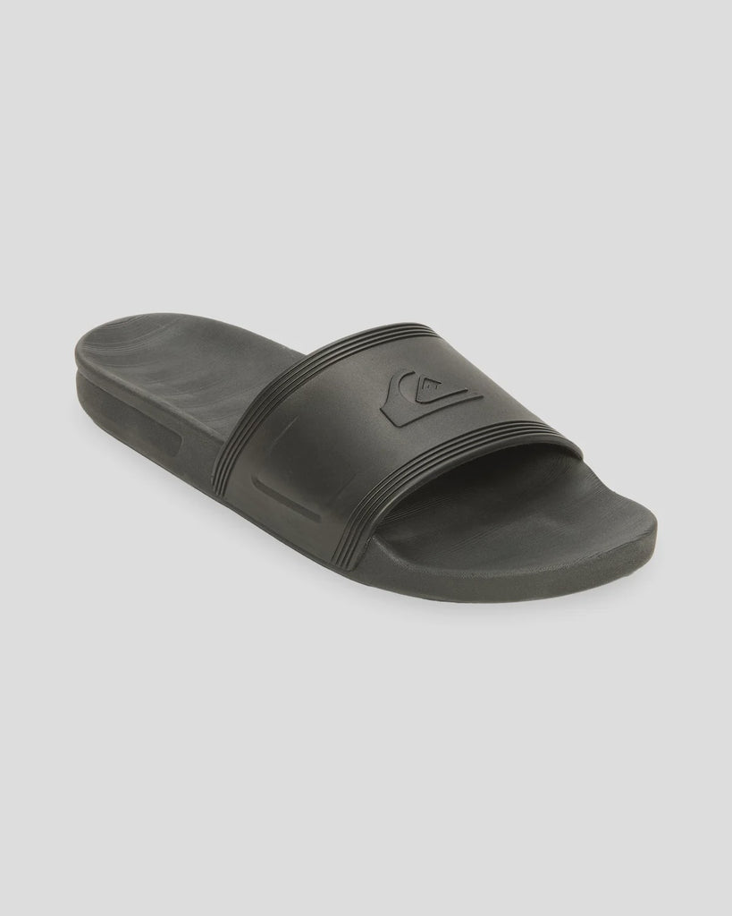 A single dark gray slide sandal with a textured strap and embossed Quiksilver logo, shown on a light gray background.
