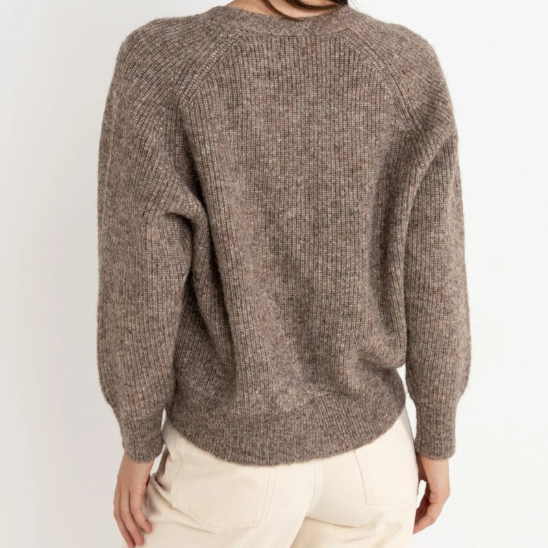 Woman wearing a brown sweater against a white background