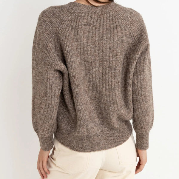 Woman wearing a brown sweater against a white background