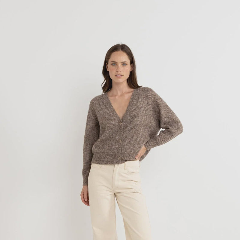 Woman wearing a brown sweater and beige pants on a white background