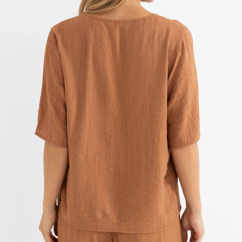 Woman wearing a brown top and pants on a white background