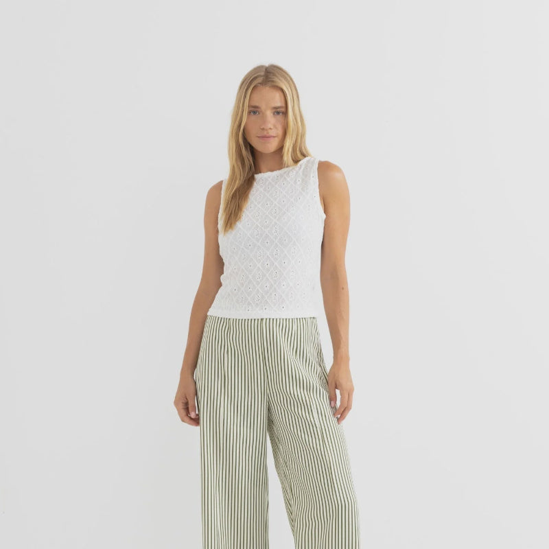 Woman wearing a white sleeveless top and striped pants on a white background