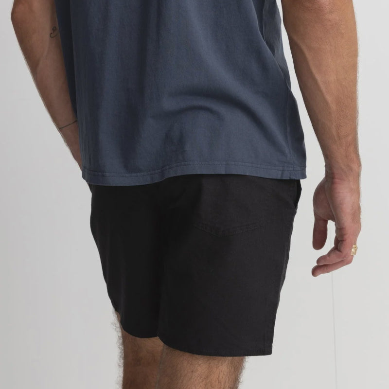 Person wearing a navy blue t-shirt and black shorts on a white background