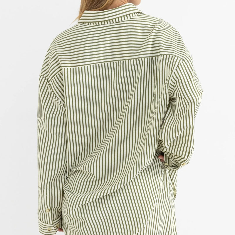 Person wearing a green and white striped shirt with shorts on a white background