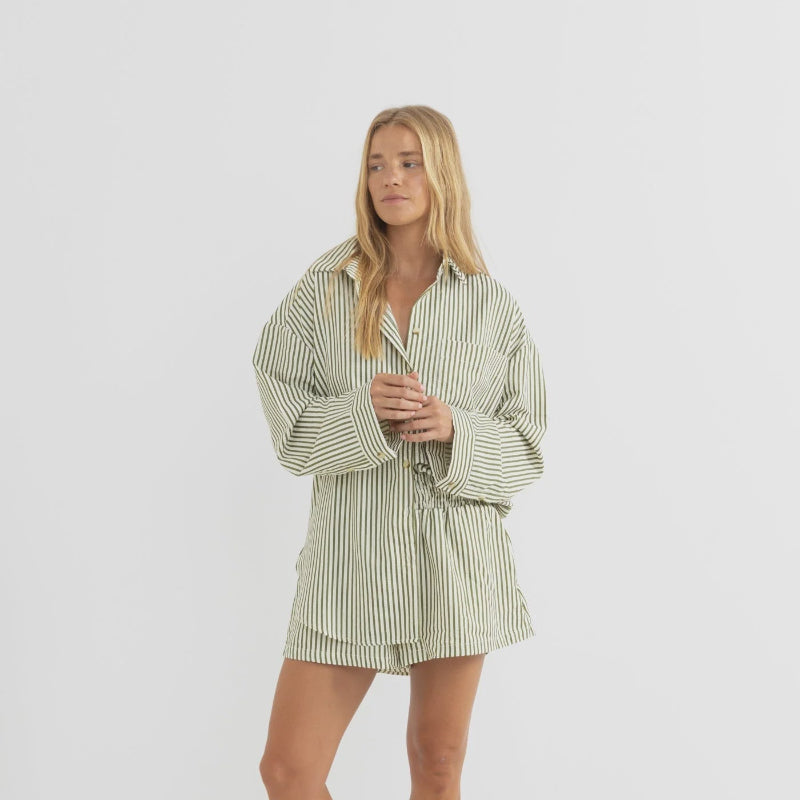 Woman wearing a green and white striped shirt and shorts on a white background