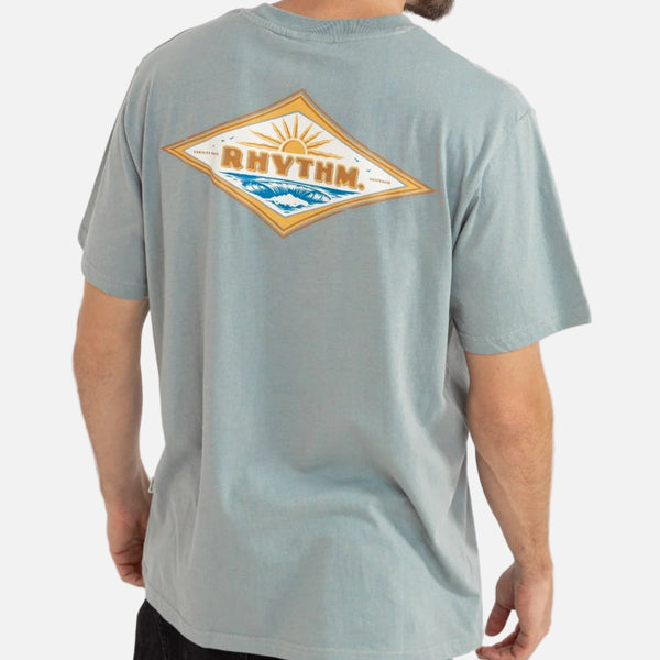Man wearing a light blue t-shirt with a 'Rhythm' logo on the back against a white background