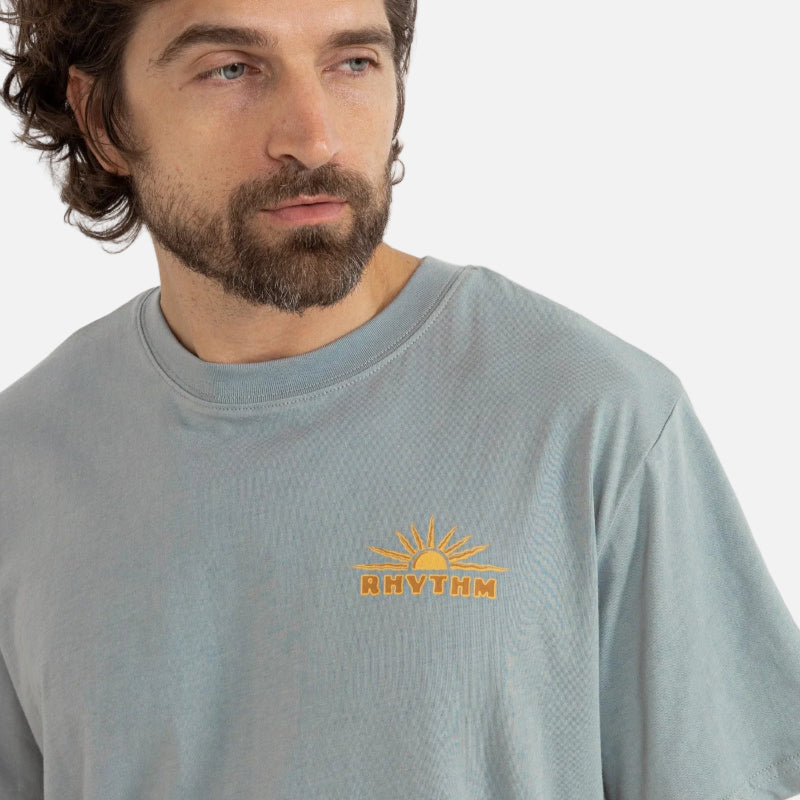 Man wearing a light green t-shirt with a logo on a white background