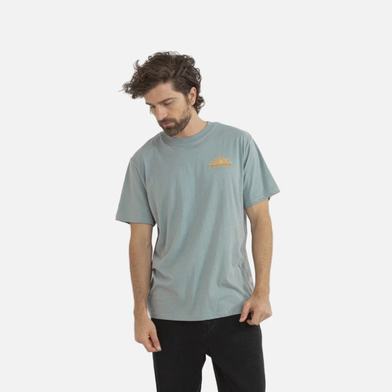 Man wearing a light green t-shirt with a logo on a white background