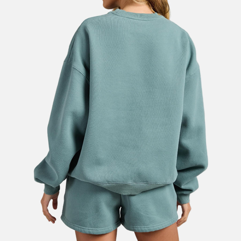 Person wearing a teal sweatshirt and shorts set on a gray background