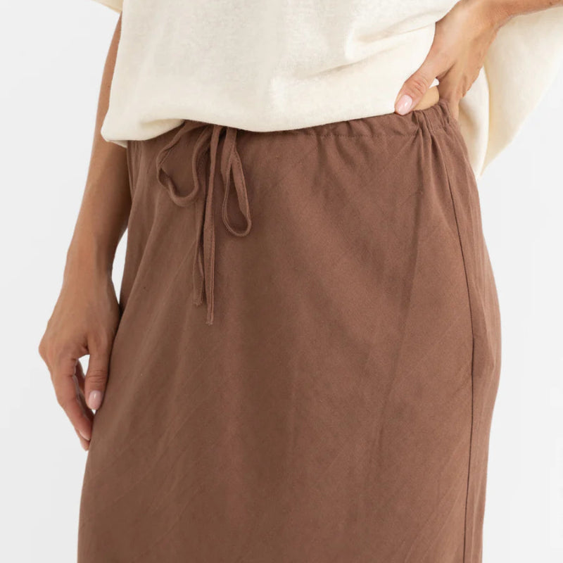 Brown drawstring pants worn with a white top on a white background