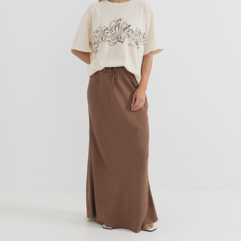 Woman wearing a beige top with embroidery and a brown skirt on a white background