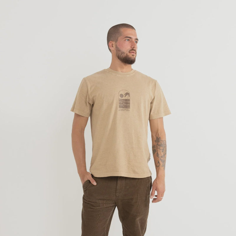 Man wearing a beige t-shirt and brown pants on a white background