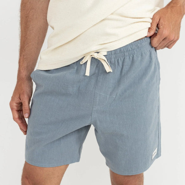 Person wearing light blue shorts with a white background