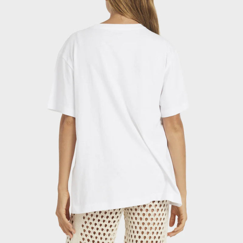 Person wearing a white t-shirt and patterned pants on a plain background