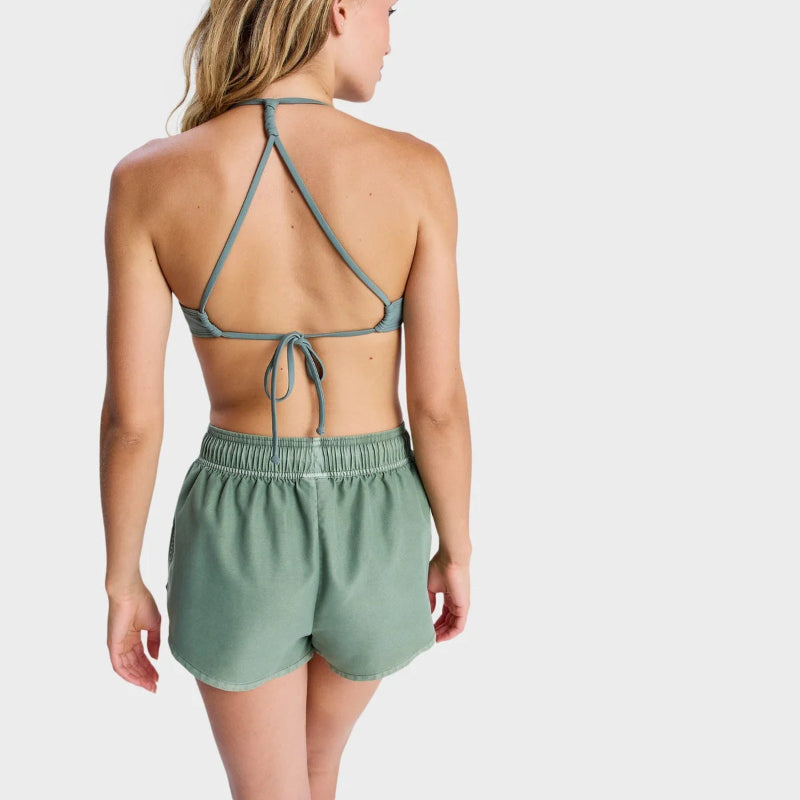 Woman wearing a green strappy top and shorts set on a white background