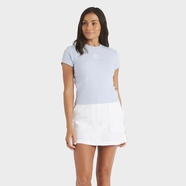 Woman wearing a light blue t-shirt and white skirt on a white background