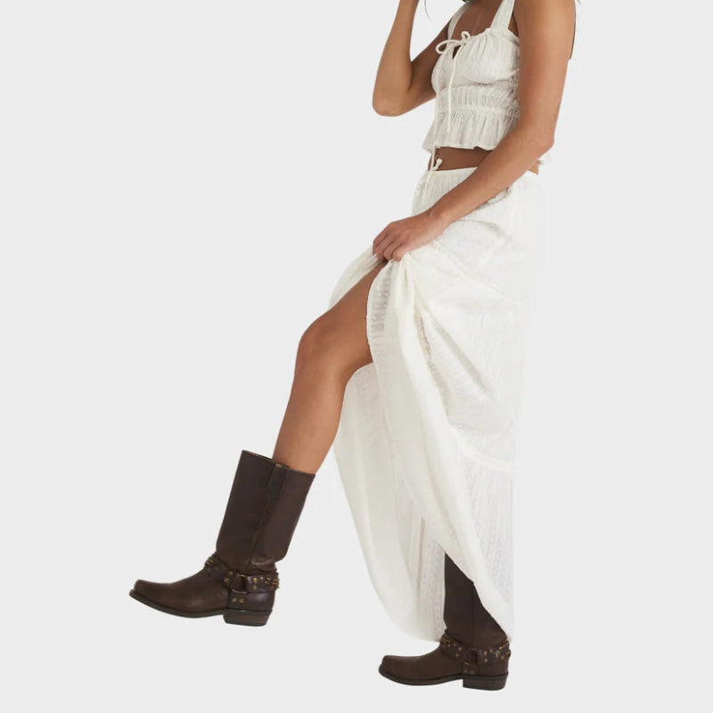 Woman wearing a white outfit with brown boots on a white background