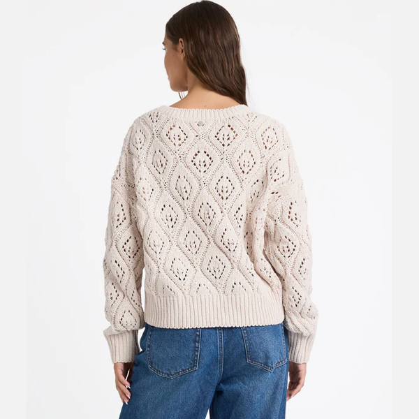 Woman wearing a cream-colored knitted sweater with a white background