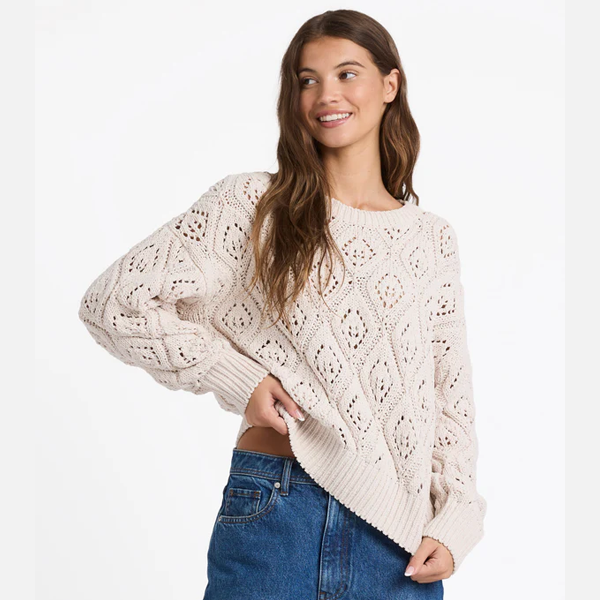 Woman wearing a beige knitted sweater and blue jeans on a white background