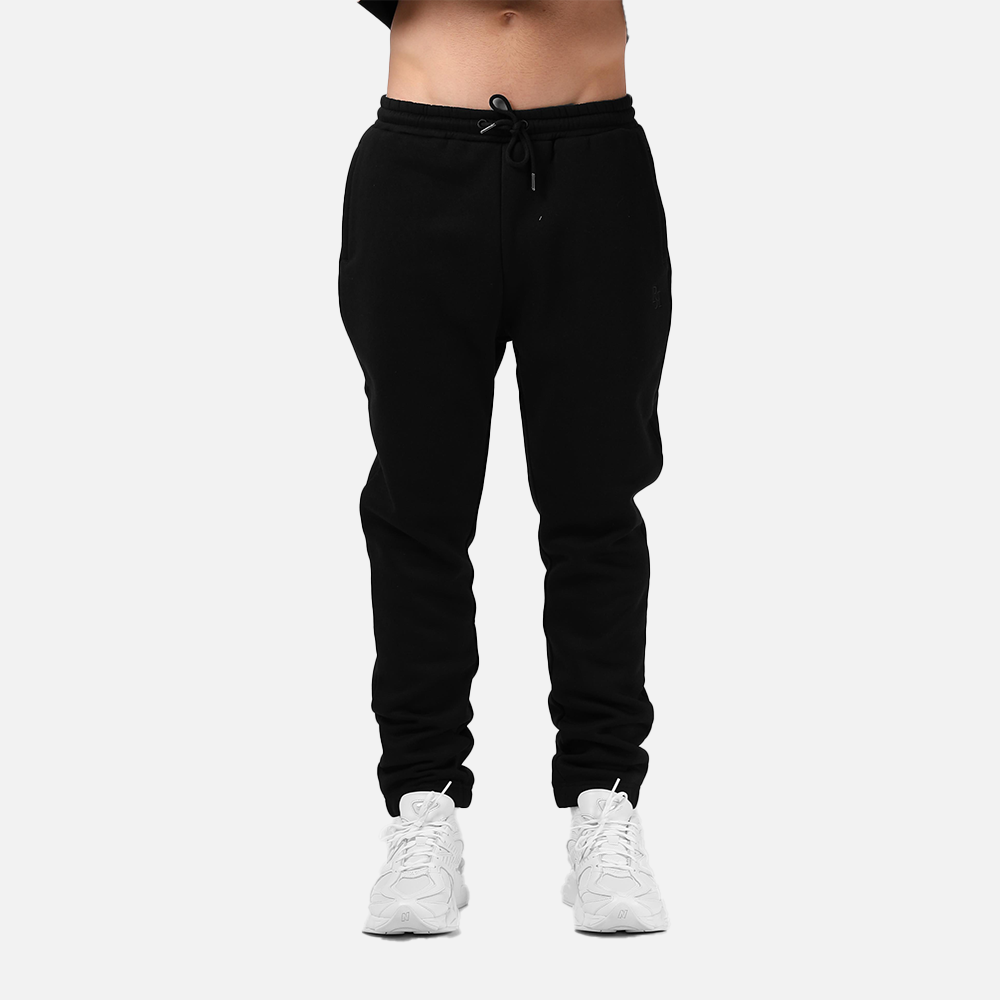 Black jogger pants worn by a person on a white background
