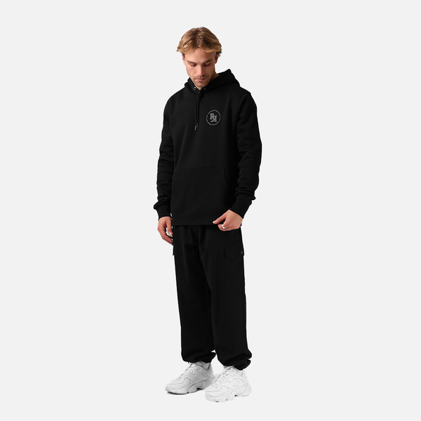 Man wearing a black tracksuit with a logo on a white background
