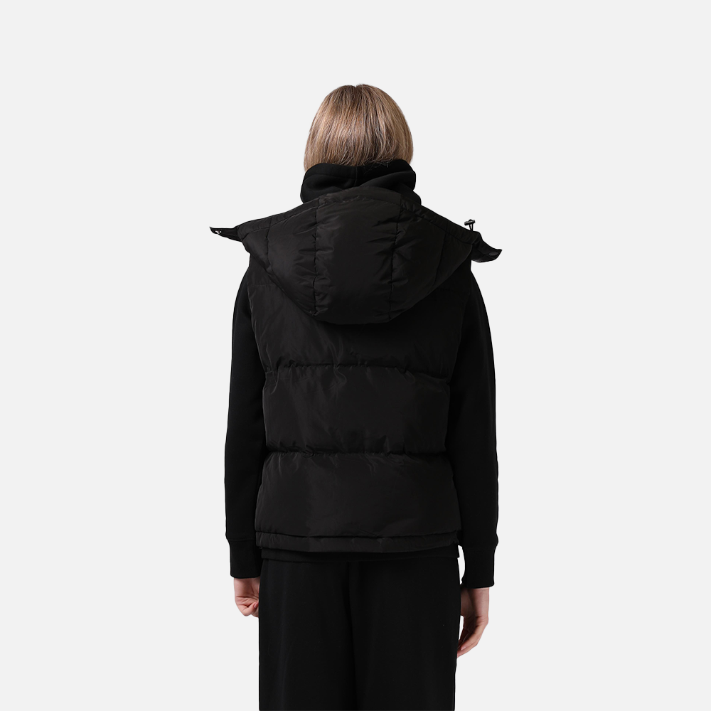 Person wearing a black puffer vest on a white background