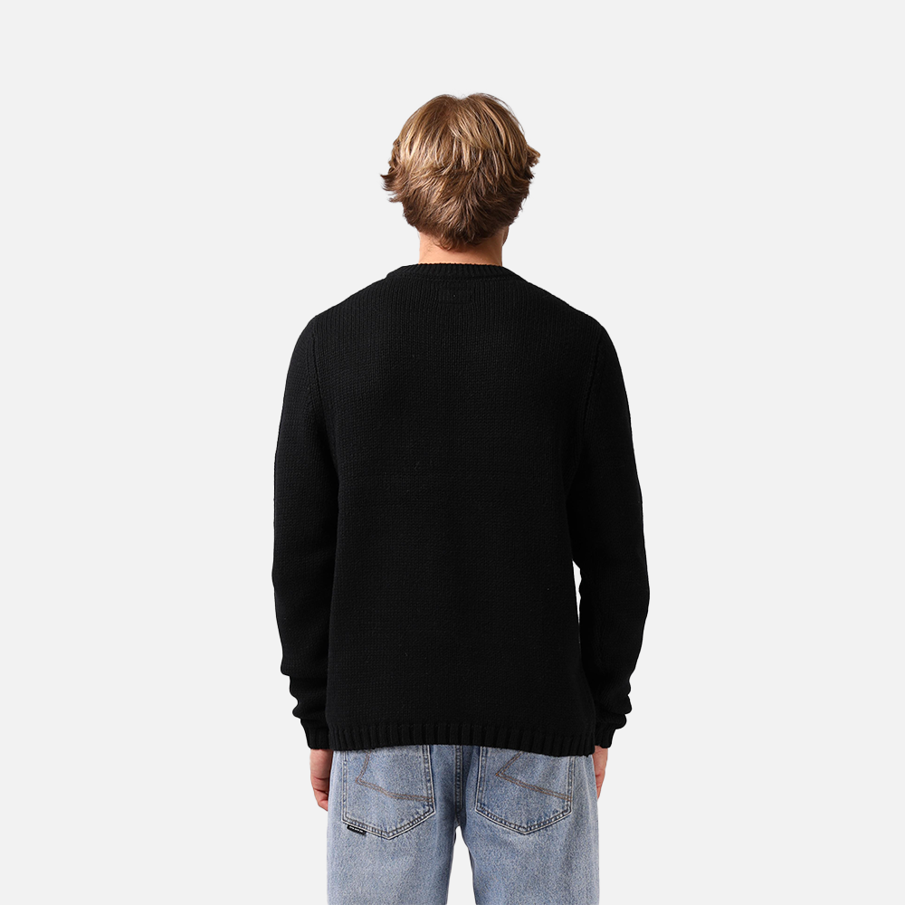 Person wearing a black sweater and light blue jeans on a white background