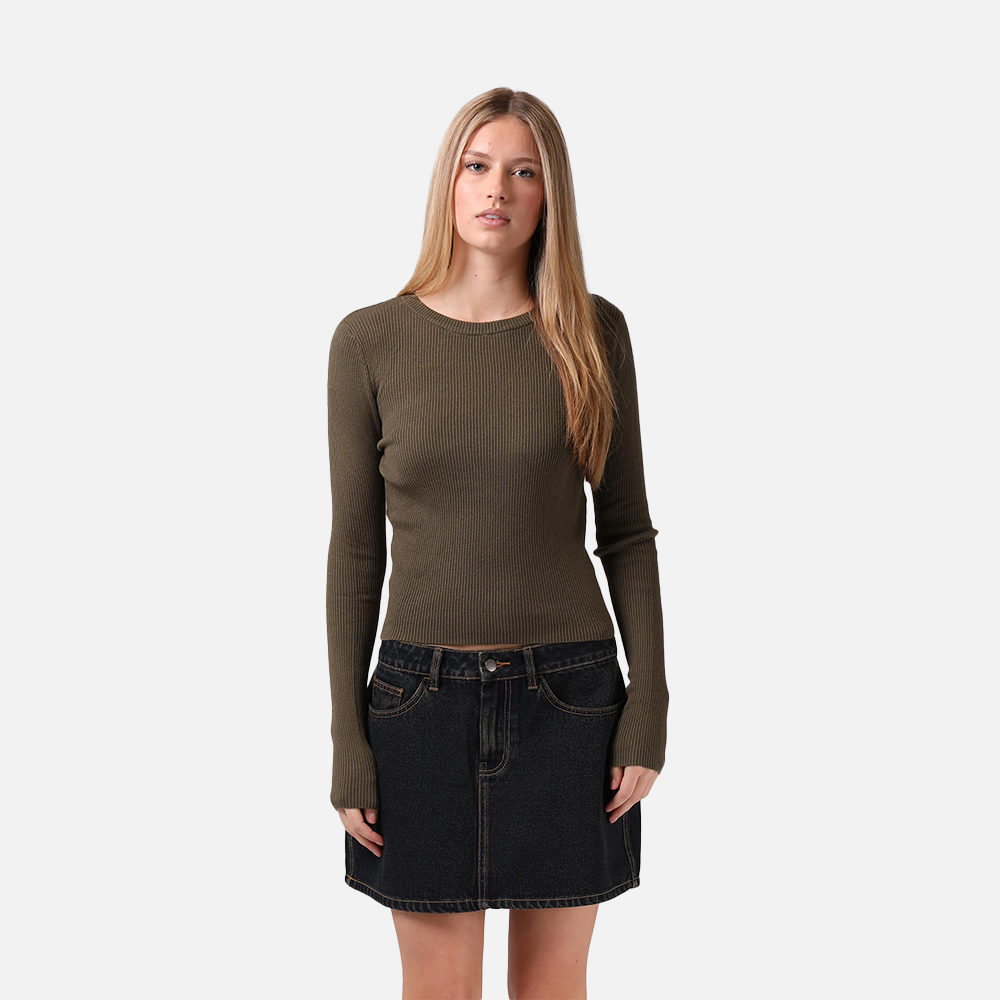 Woman wearing a green ribbed sweater and black denim skirt on a white background