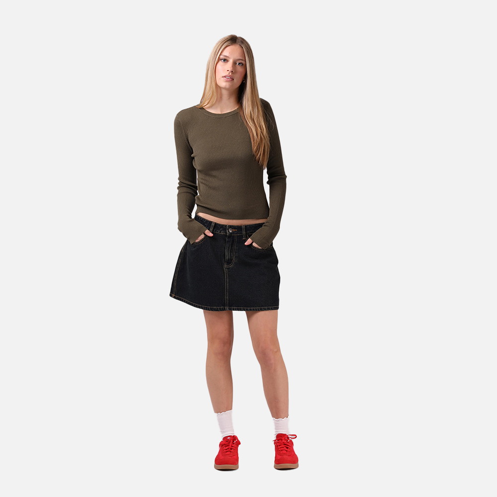 Woman wearing a green sweater and black skirt with red shoes on a white background