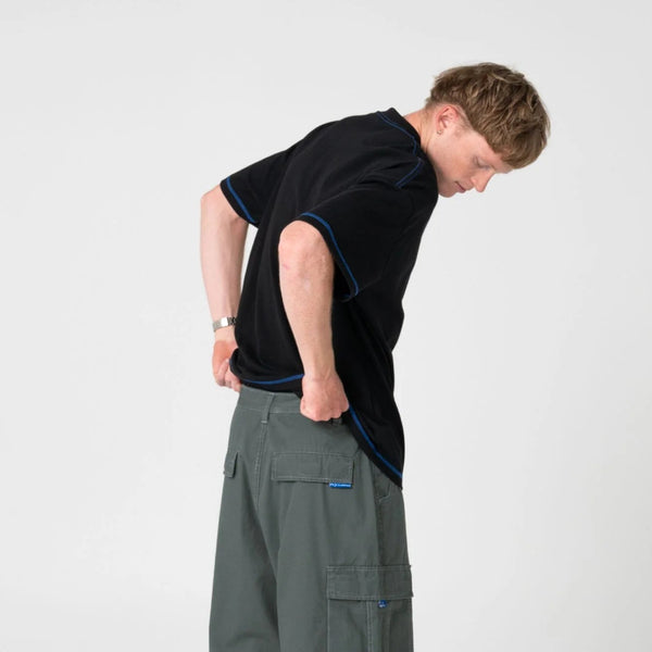 Person wearing a black t-shirt and green cargo shorts on a white background
