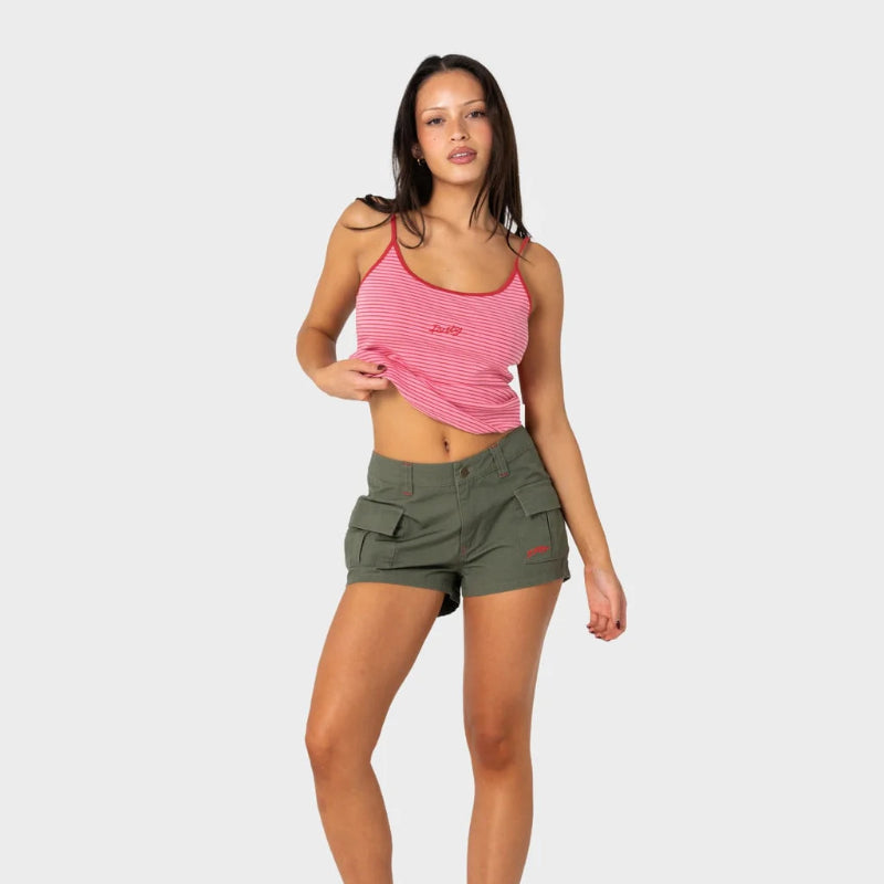 Woman wearing a pink tank top and green shorts on a white background
