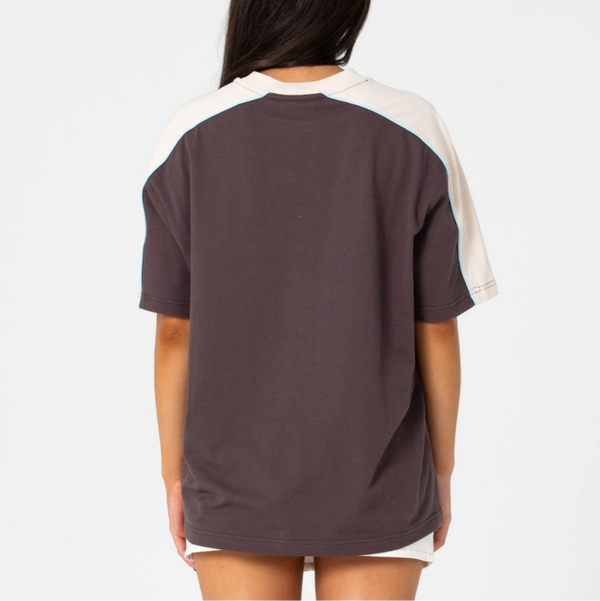 Person wearing a dark brown t-shirt with white sleeves on a white background