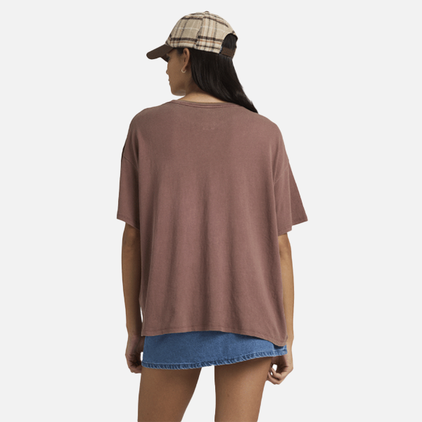 Person wearing a brown oversized t-shirt and plaid cap on a white background