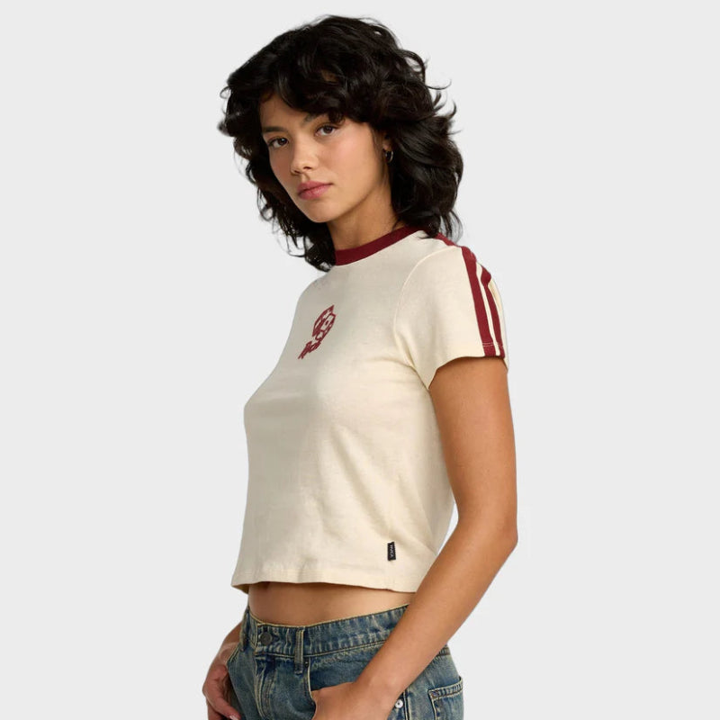 Woman wearing a cream-colored crop top with red accents and blue jeans on a white background