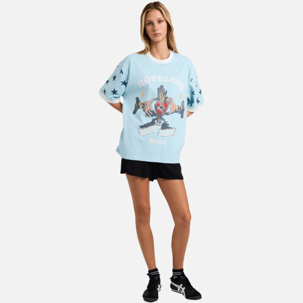 Woman wearing a light blue graphic t-shirt with black shorts on a white background