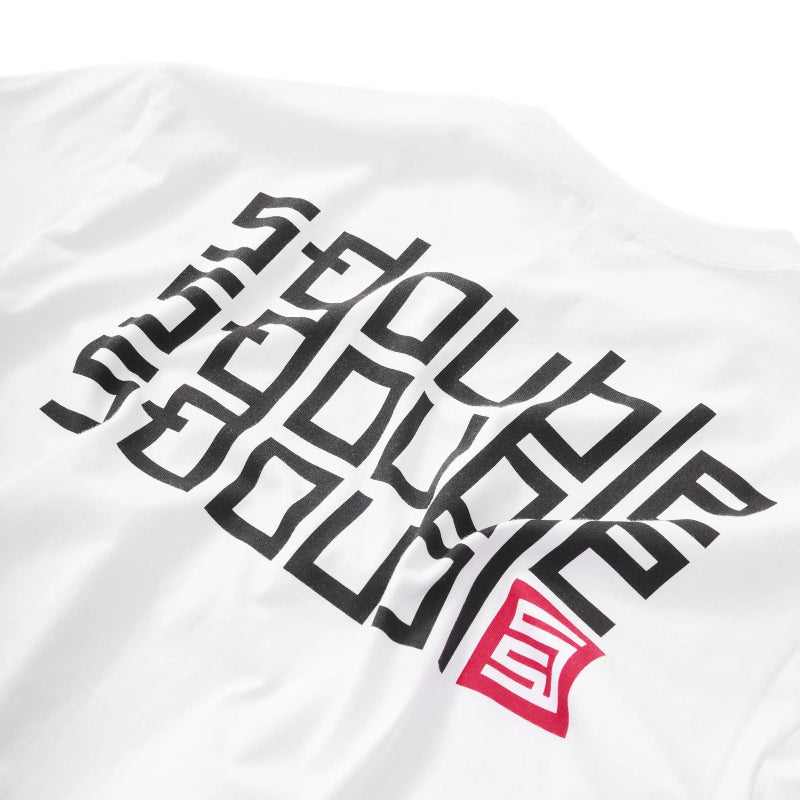 A close-up of a white t-shirt featuring a large black geometric graphic print and a red square logo on the front.