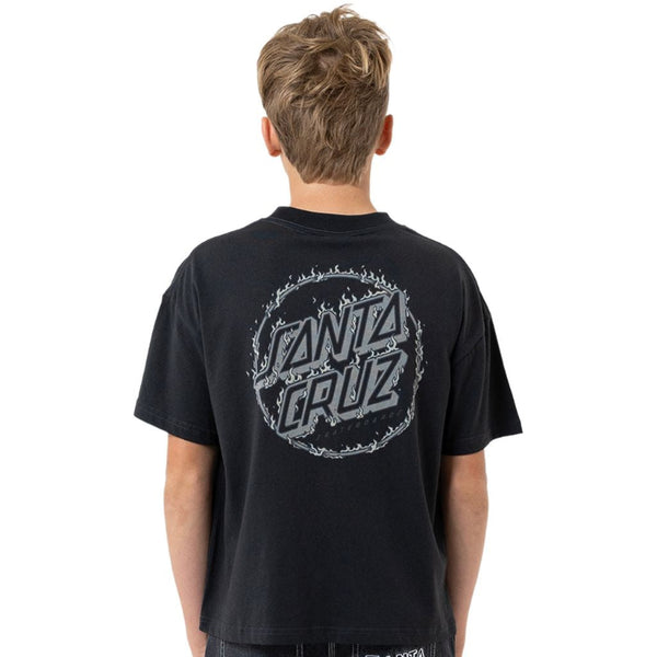 A boy viewed from behind wearing a black Santa Cruz t-shirt with a large gray graphic on the back and dark wash jeans.